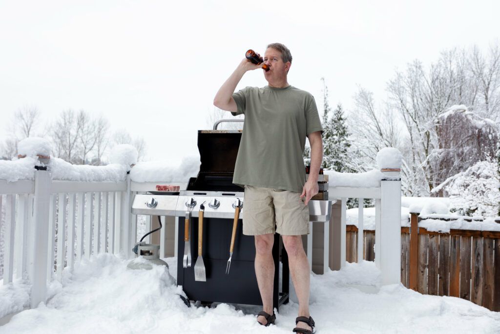 Homme avec sa bière devant le barbecue l