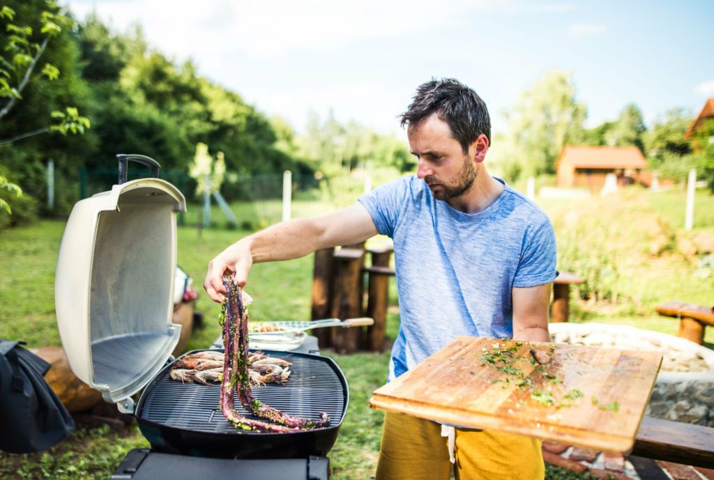 homme qui fait griller sur barbecue électrique
